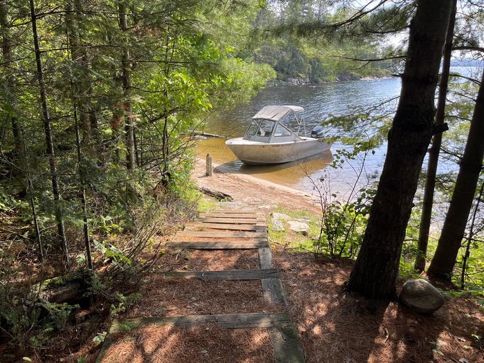 View from shore of sand landing, looking down the stairs with a boat tied to the mooring post.Shore out view of sand landing at campsite.