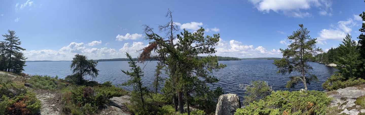Panorama view from campsite overlooking the water with a rugged shoreline of trees.Panorama