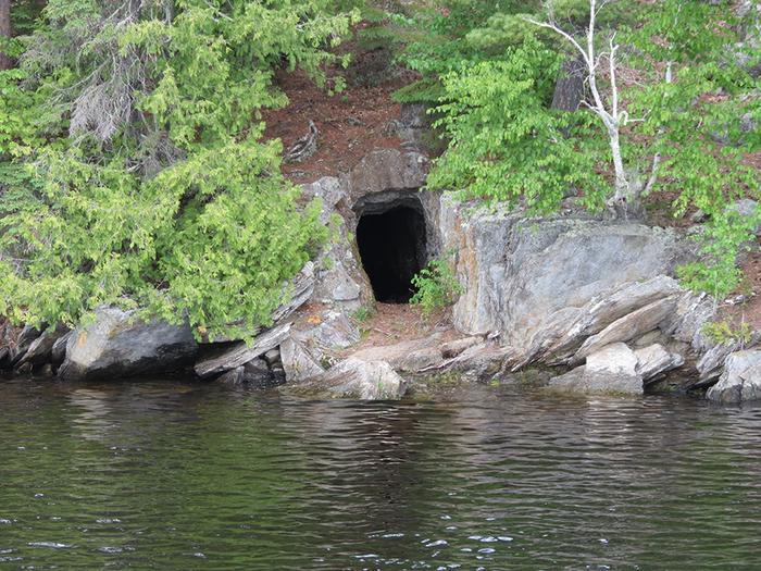 Bushyhead mine adit with a hole in the side of the island along the shoreline of the water.Bushyhead mine adit