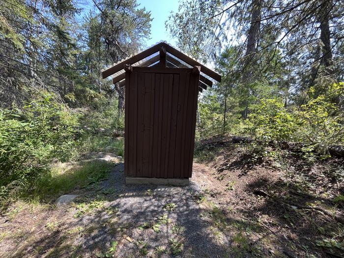 Outhouse at campsite that is brown with the privy inside.Outhouse at campsite