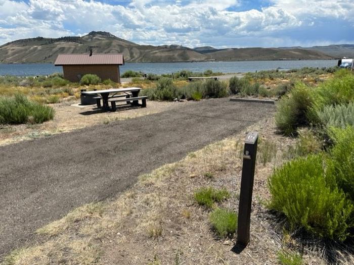 Campsite 15: driveway, picnic table, and firepit. Set in sagebrush with view of vault toilet, mesas and reservoir.Loop A Campsite 15: driveway, picnic table, and firepit.