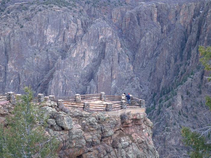 Park visitors admire the view of Black Canyon of the Gunnison's high cliff walls at Gunnison Point.