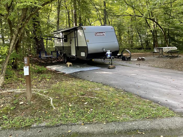 A blacktop surface with a parked camper.C-8 has a fire ring and picnic table.