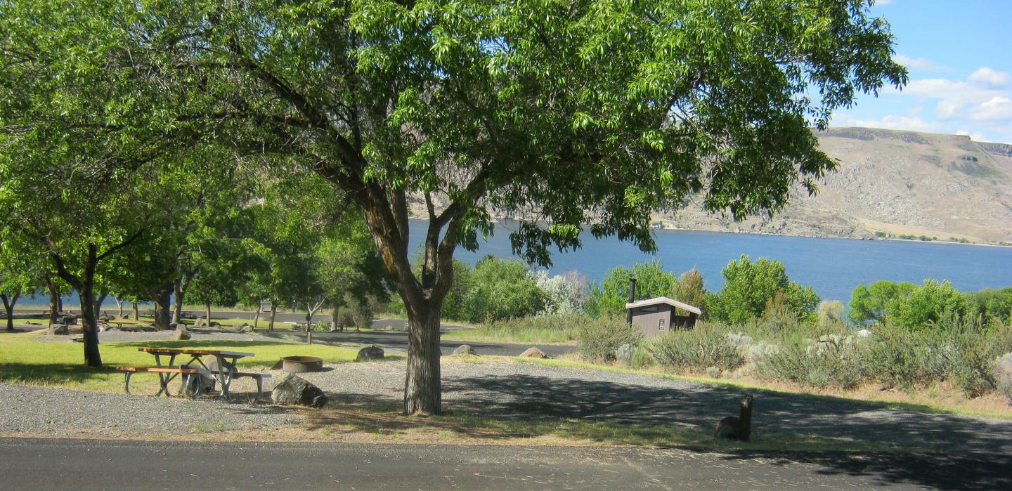 Site 22Back-in gravel parking. Fire grate at back of parking area. Lake Roosevelt in background. Downward slope to Swim Beach/Day Use Area.