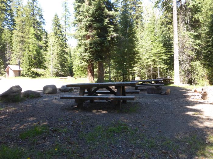 Picnic tables, fire ring, gravel parking area, and vault toilet.Picnic tables and fire ring next to the gravel parking area. Vault toilet in the background.