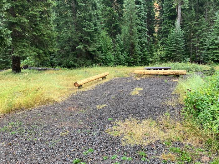 Gravel parking pad with new log barriers and picnic table. Stream in the background.Log barriers recently replaced at 1 of the gravel parking sites.