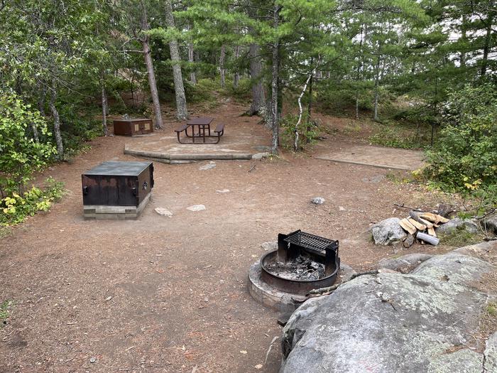 View looking into campsite core of the fire ring, bear lockers, picnic table, and a tent pad.View of campsite core