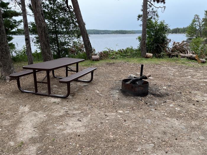 View looking out from campsite of the picnic table and fire ring with water in the background.View looking out from campsite