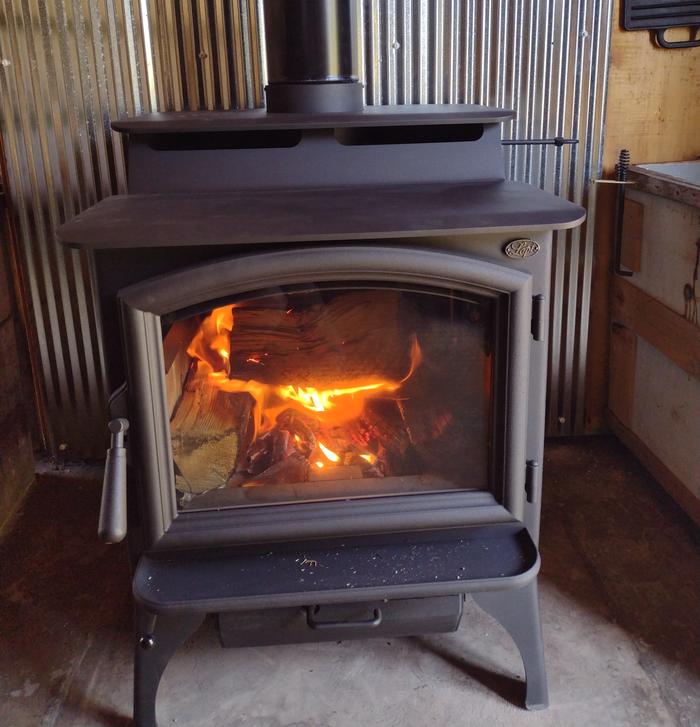 Wood stove with fire burning insideWest Fork Cabin wood stove