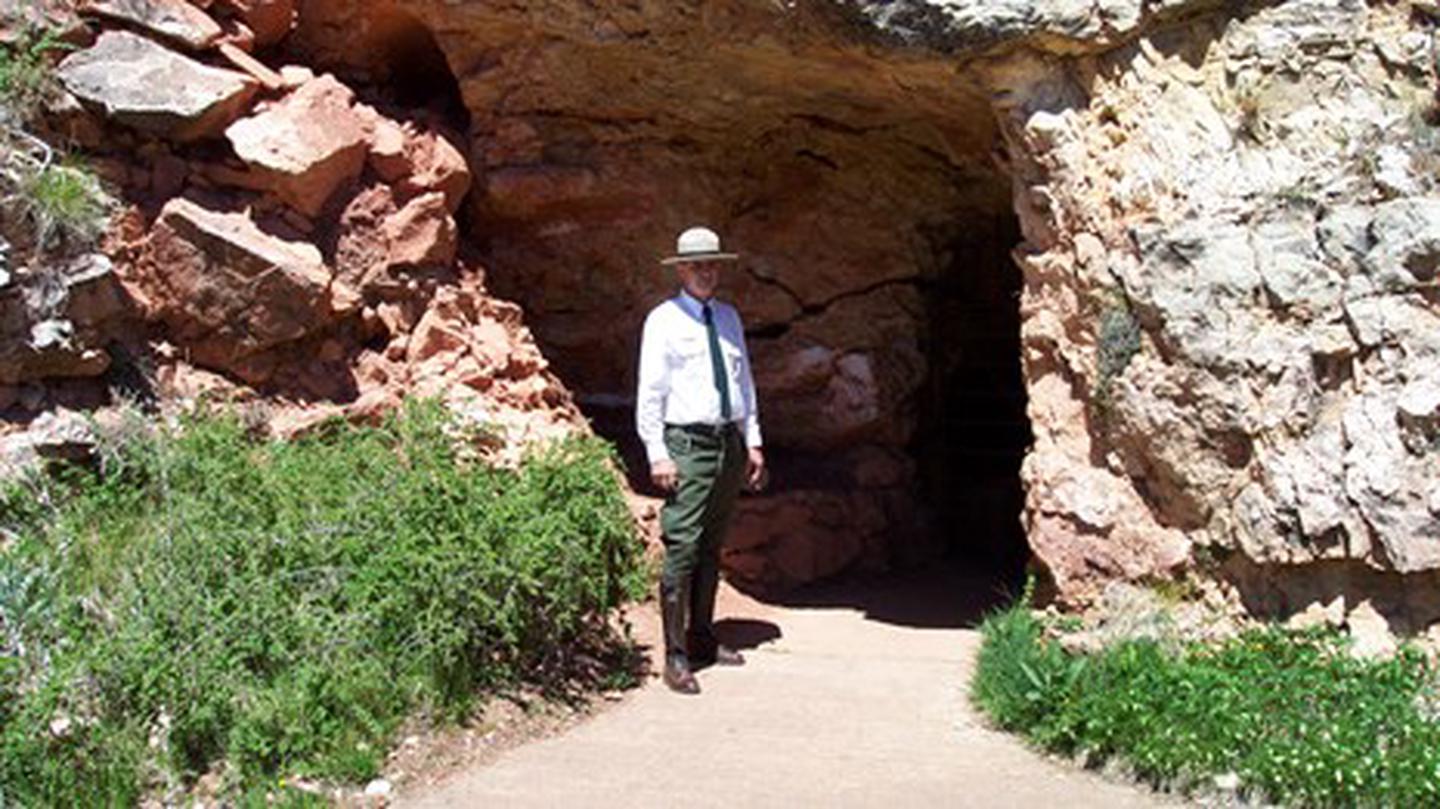 A ranger dressed in the historic park uniform waits at the historic entrance to Jewel Cave.