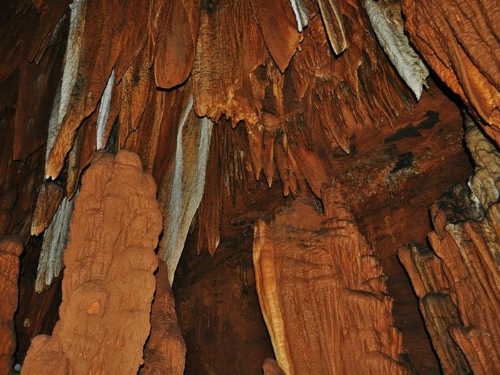 Copper-colored stalactites hang from the ceiling of Big Spring Cave