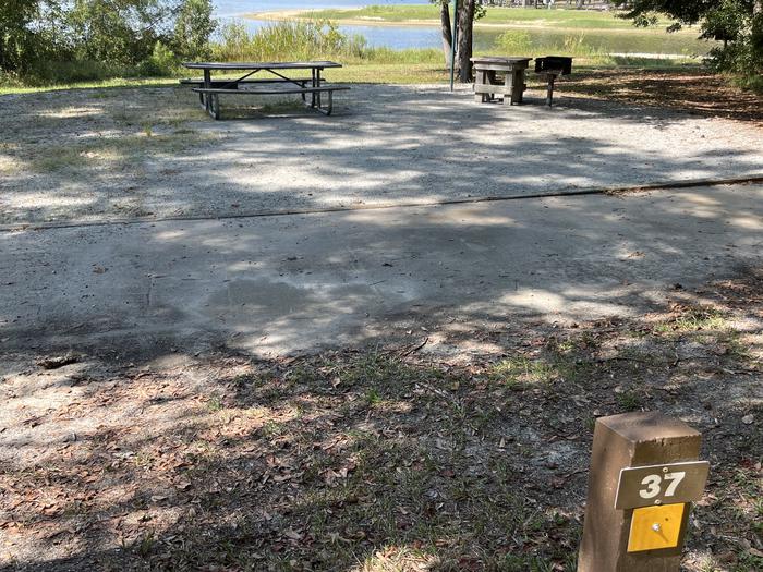 A photo of Site 037 of Loop OAKW at WHITE OAK (CREEK) CAMPGROUND with Picnic Table, Electricity Hookup, Fire Pit, Shade, Waterfront, Lantern Pole, Water Hookup