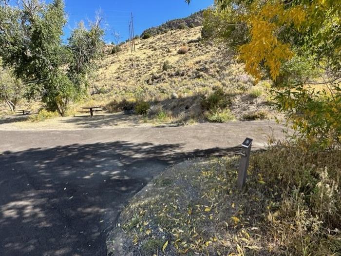 Campsite 5: driveway, picnic table, and firepit. Set in sagebrush and trees.