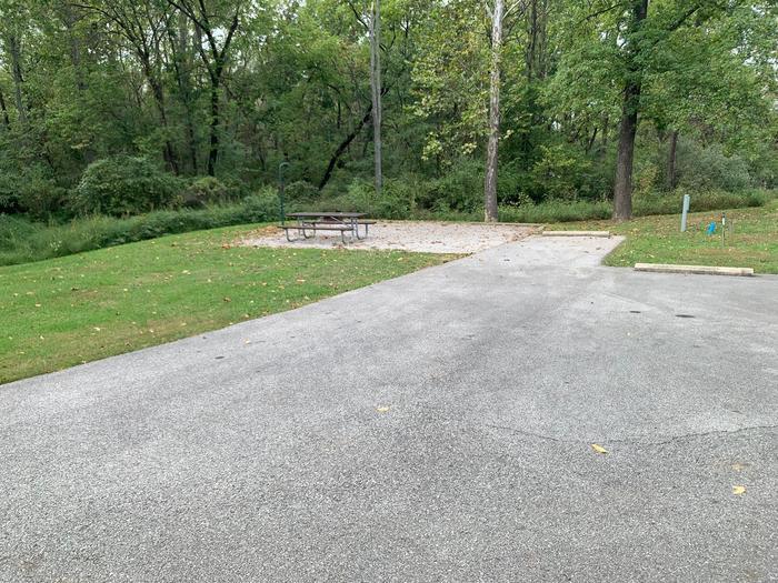 picnic table and fire pit to the left of camp pad, electric, water, and extra parking to the right of pad.