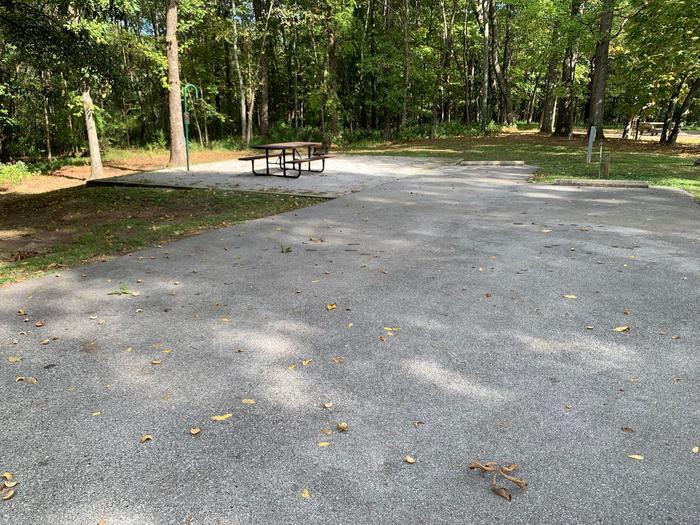 picnic table and fire pit to the left of camp pad, electric, water, and extra parking to the right of pad.