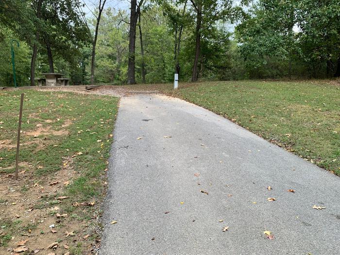 This site has a picnic table and fire pit on the left side of the paved pads. The hookups for this site are located to the right rear side of the paved parking pad. This site has an additional pad for camping supplies. 