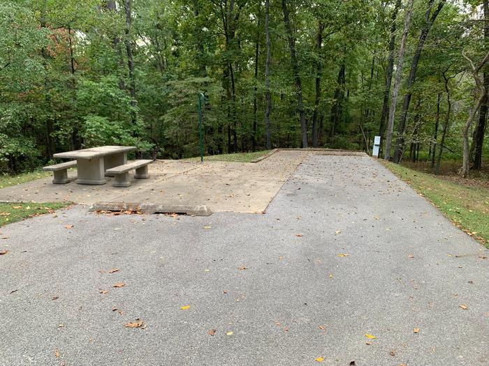  This site has many trees surrounding it, providing lots of shade. The fire pit and picnic table (sitting on a concrete pad) are located on the left side of the paved pad. Hookups are on the right side. This is a handicap accessible site. 
