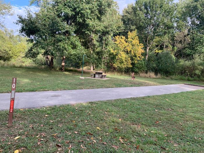 This site has a picnic table and firepit located on the left side of the paved parking pad. Hookups are to the right rear side of the site. There are many trees at the rear of the site and near a comfort station.