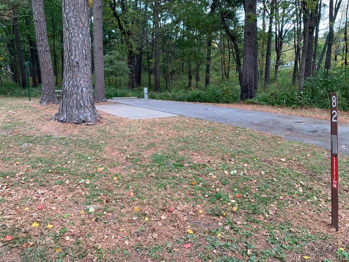 This site is nestled in a tree line with the picnic table and fire pit located on the left side of the paved parking/camping pad and the hookups are located to the right of the pad. 