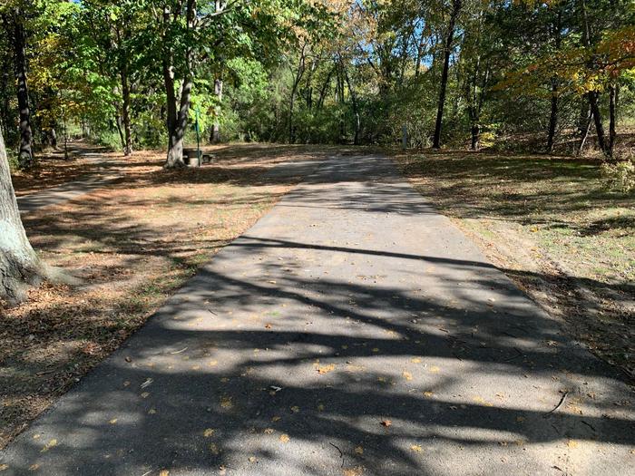 This site has a picnic table and firepit located on the left side of the paved parking pad. Hookups are to the right rear side of the site. There are many trees at the rear of the site and near a walking/biking path.