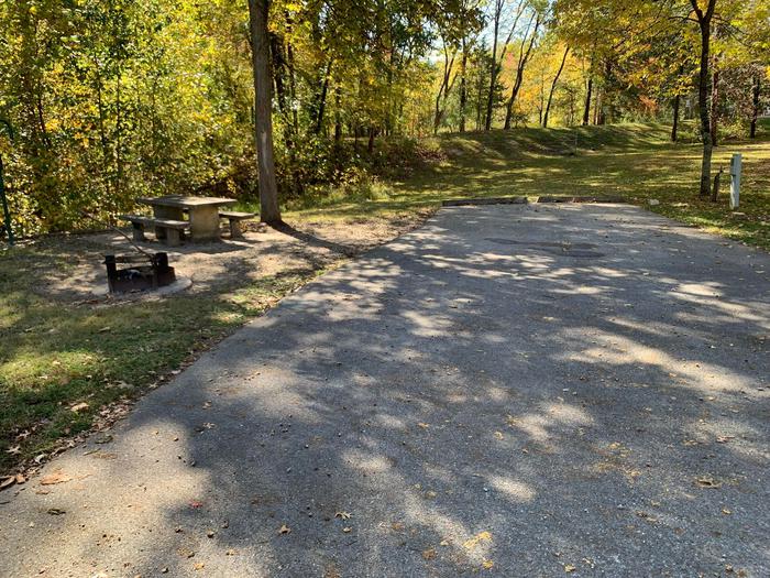The picnic table is located on a paved pad to the left side on the main camping pad with the fire pit located near by. All hookups are located on the left side. This site is full hookup and is within walking distance to the comfort station.  