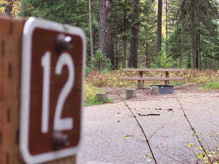 A photo of Site SLS12 in Loop 1 at Seeley Lake Lolo Campground (MT) with campsite marker, parking area, picnic table, campfire ring.  A photo of Site SLS12 at Seeley Lake Lolo Campground (MT) with campsite marker, parking area, picnic table, campfire ring.
