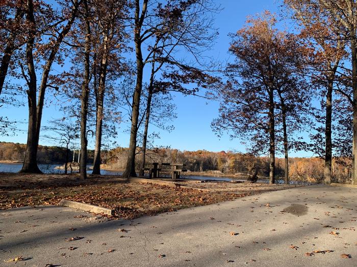 This site has a perfect view of the lake. Picnic table and fire pit are located to the left of the paved parking/camping pad. The hookups are on the right side of the pad. This site has a picnic table and fire pit to the left side of the paved parking/camping pad. The hookups are on the right side of the pad. There is a tree line on the right side of the pad also. 