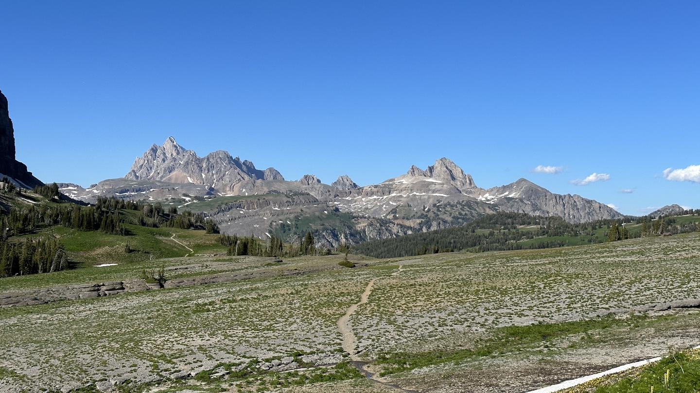Blue sky with mountain peaks and trail Tetons in the background across the Death Canyon Shelf, Grand Teton National Park 
