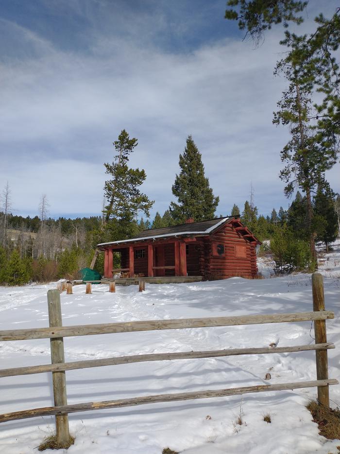 High Rye Cabin, view from parking lot,  Red Cabin with snow on the ground surrounded by green treesHigh Rye Cabin viewed from parking area