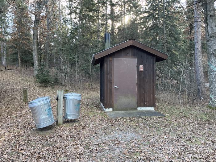 A photo of a vault toilet and trash receptacle at Wagner Lake (MI)
