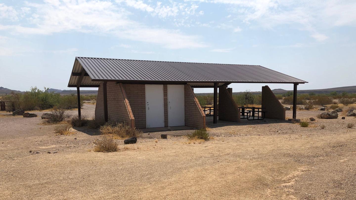 A long covered pavilion provides a shaded picnic area in the desert