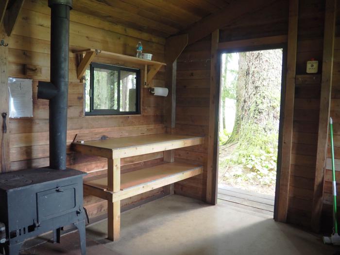 Harding River Cabin interior wood shelves, door open and stoveHarding River Cabin interior