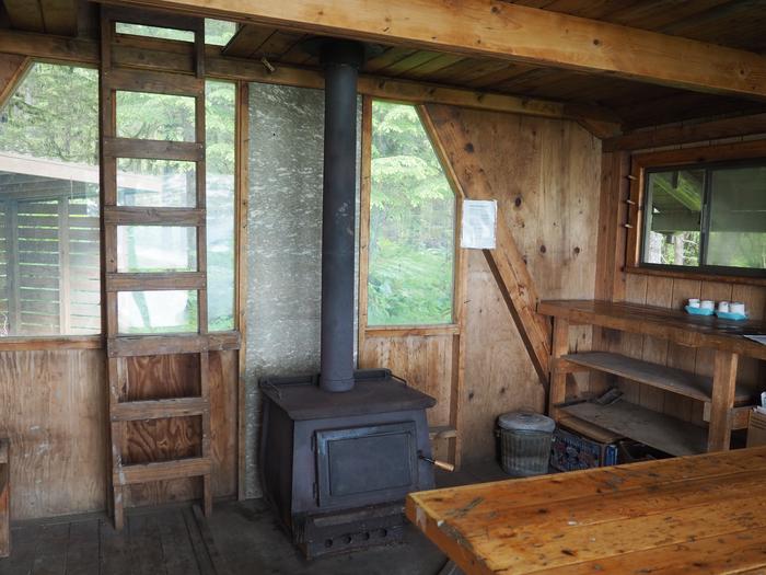 Interior of wood cabin with shelves, tables, stove and ladder to loftInterior Mallard Slough Cabin