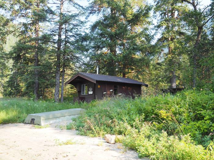 Marten Lake Cabin with overturned small skiff in front with grasses and trees surrounding itMarten Lake Cabin exterior