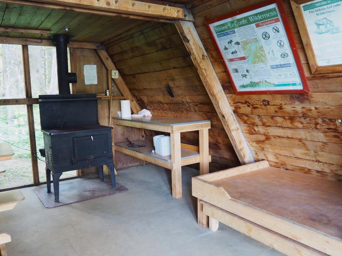 Mount Rynda Cabin interior with wood cabinet and bed with stoveMount Rynda Cabin interior