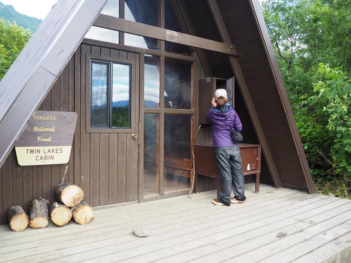 A person standing at Twin Lakes Cabin entrance next to a bear boxTwin Lakes Cabin (AK)