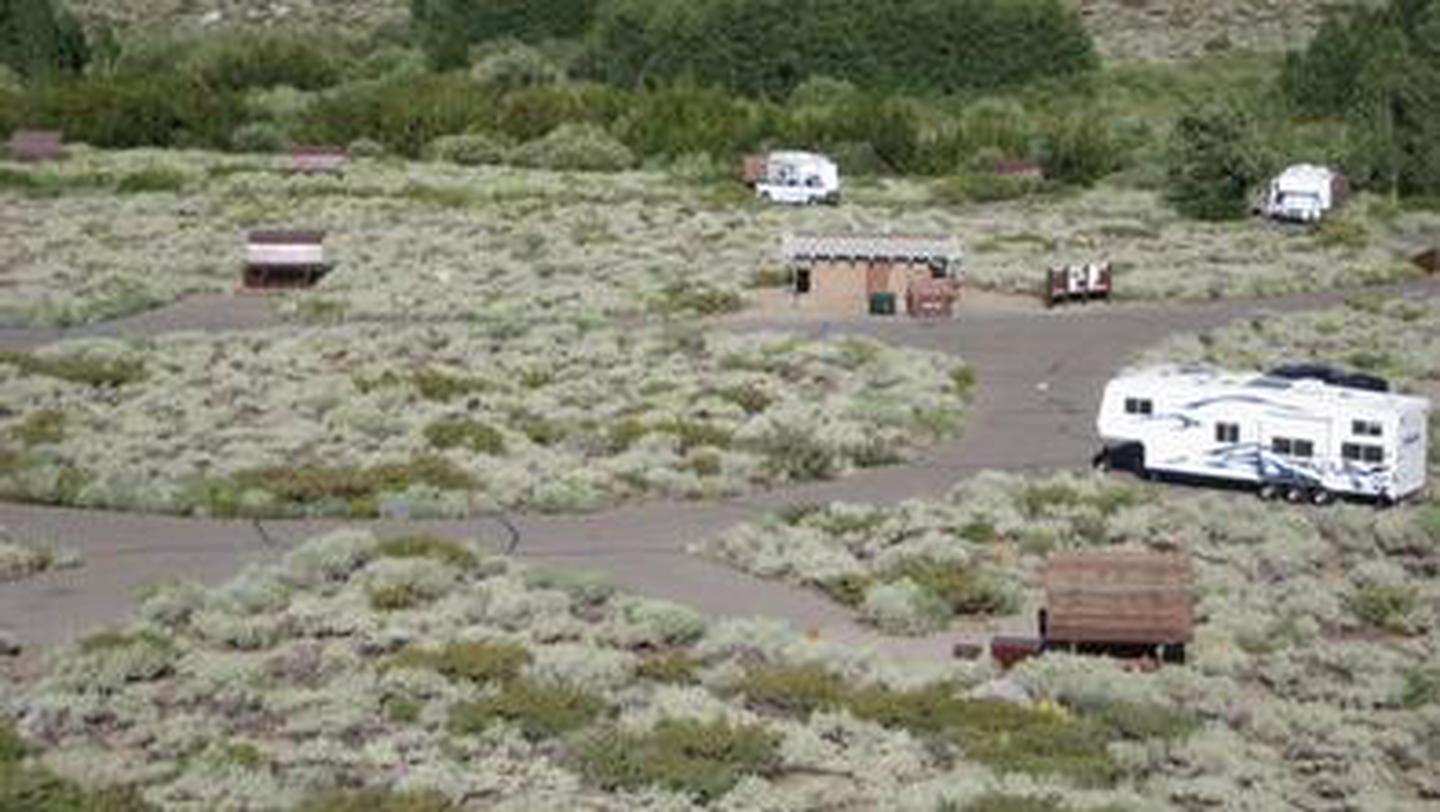 A shrub grass campground with several RVs parked in campsite spursMcGee Creek Campground