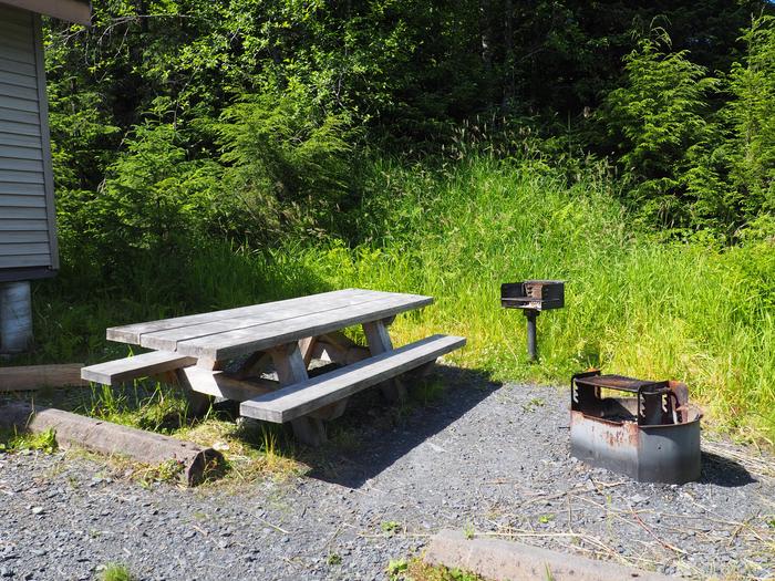 Deep Bay Cabin picnic area with picnic table, bbq and firepit on gravel with grass aroundDeep Bay Cabin picnic area