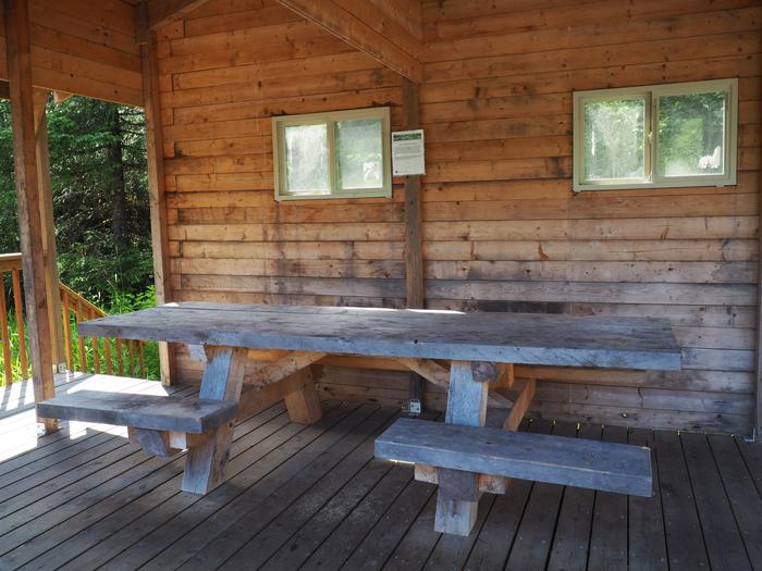 Deep Bay Cabin covered porch with picnic table under on wood patioDeep Bay Cabin covered porch