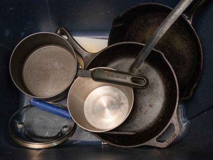 A zoomed in image of clean and dry pots and pans inside a blue plastic tote.Pots and pans are provided for visitor use. They are located in the kitchen area inside a blue bin.