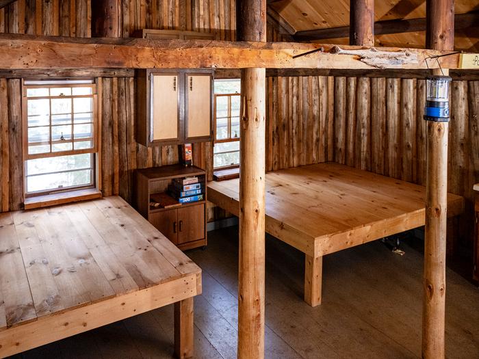 Overhead view of two square wooden sleeping platforms inside a small wooden hut.Make sure to bring your own camping gear! Elevated wooden sleeping platforms are available inside the hut.
