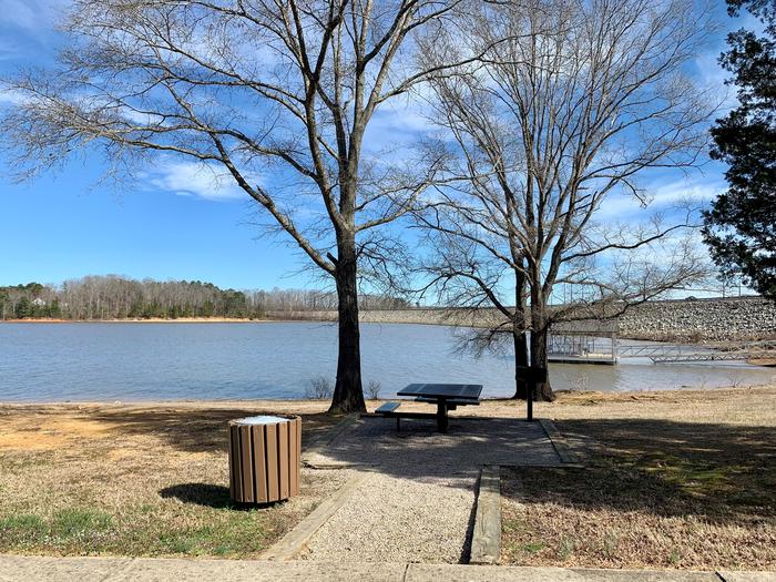 This is an accessible picnic area.This is an accessible picnic area with a picnic table and trash can. 
