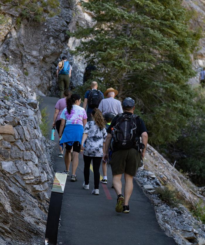 People hiking up a steep, narrow, paved trailTrail to Timpanogos Cave