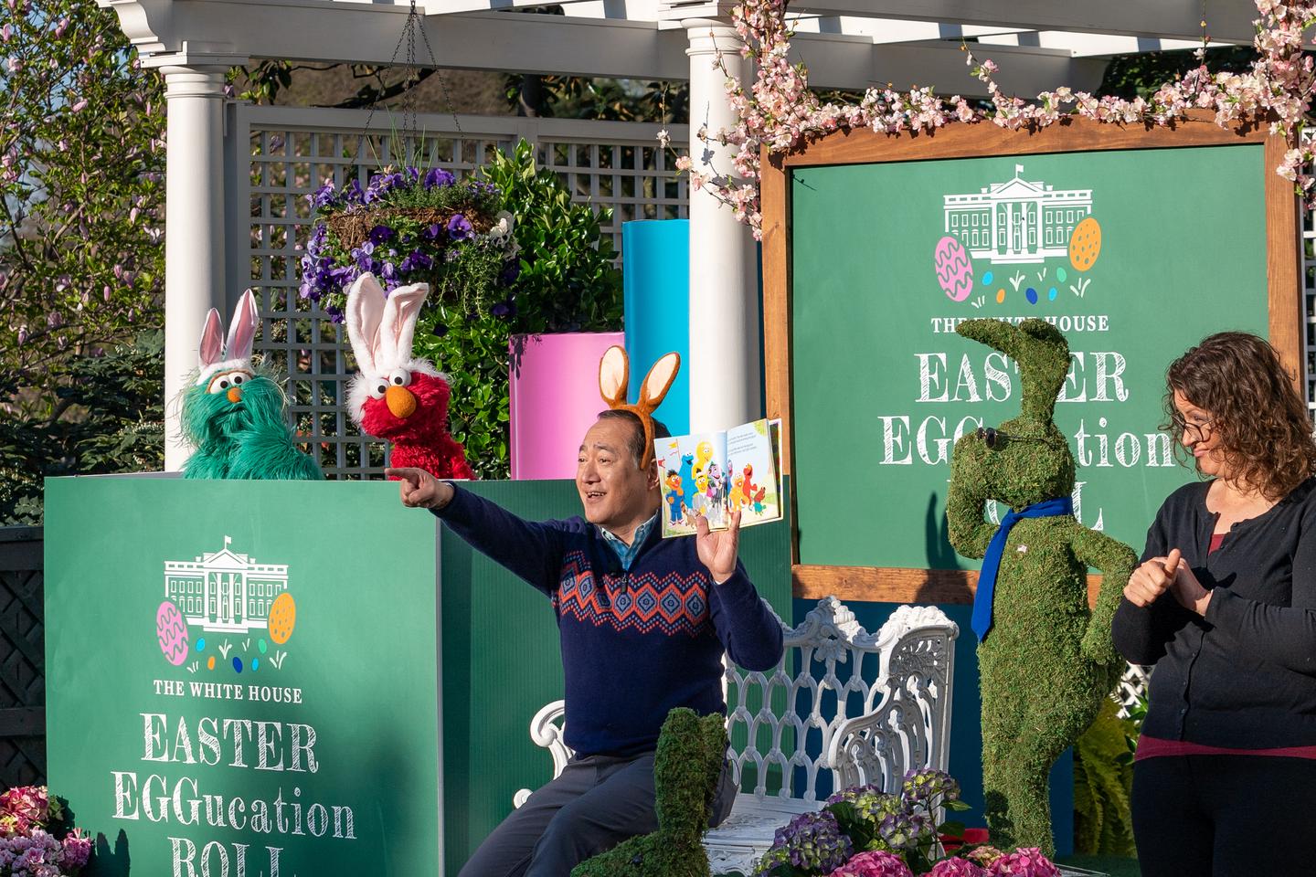 Staff member and ASL interpreter reading a Sesame Street book to children during White House Easter Egg Roll 