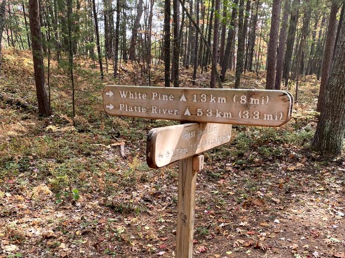 Wooden trail sign showing hiking distances.