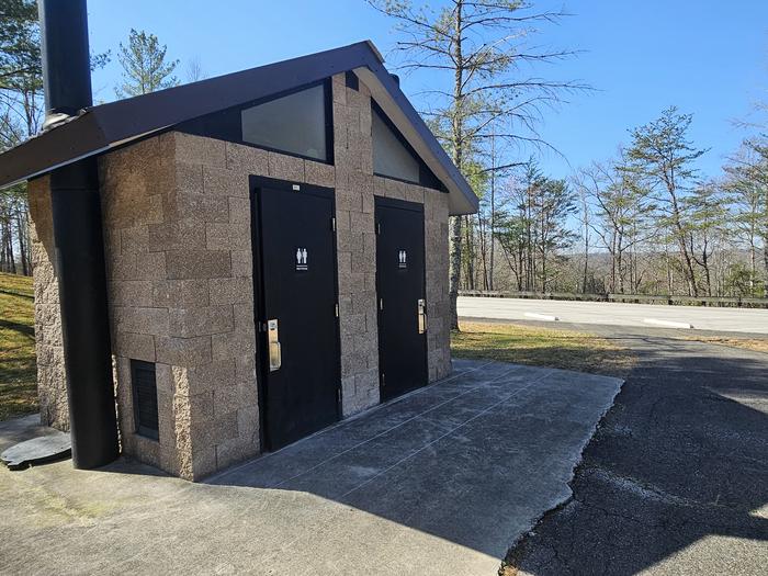 Brick building with two doors on front standing near a parking lot.Blue Heron Overlook vault toilet facilities in the parking lot.