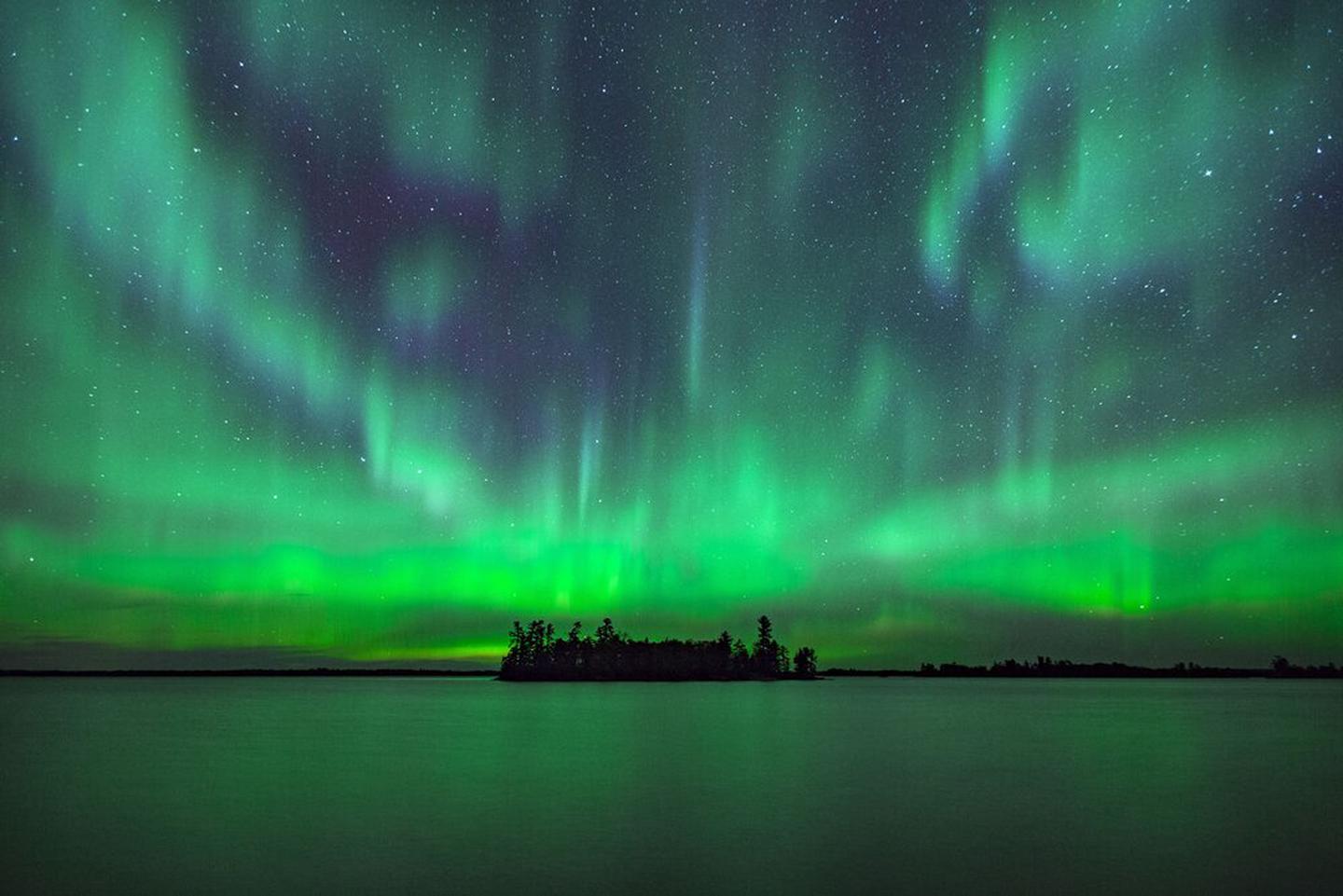 Northern Lights on display with island in foreground 