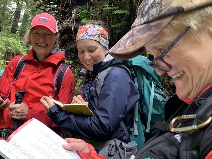 a group of happy people looking up information in a plant guide and jotting it down Learning how to identify plants can lead to a lifetime of enjoyment exploring plants in nature.