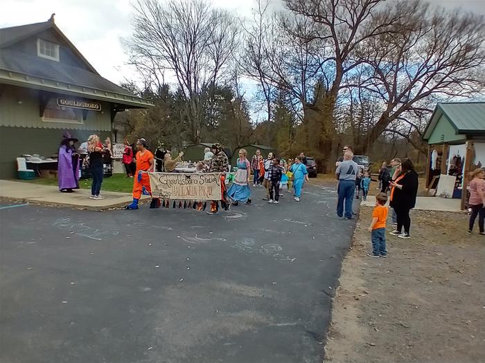 A parade of people in costume march around the station.Ghoulsboro Station Halloween Parade