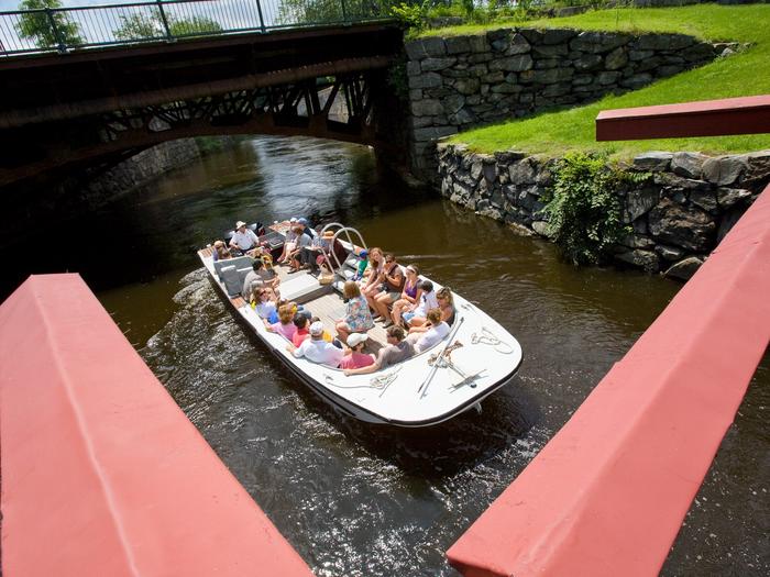 Group of visitors in an open top boat float on a canalGroup of visitors on a canal boat tour on the Pawtucket Canal